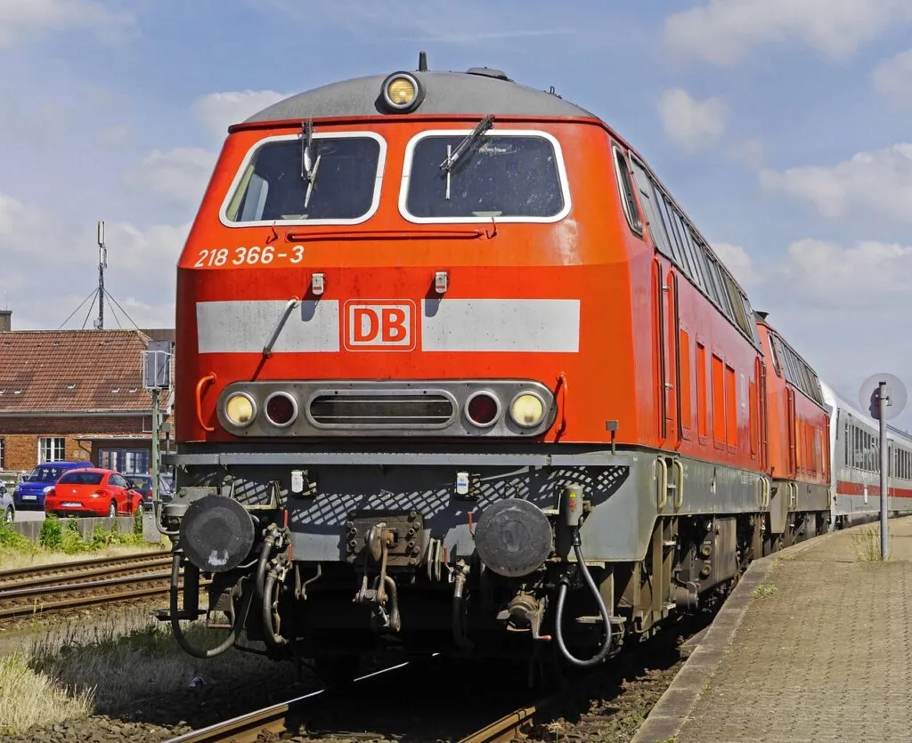 Red and white DB electric locomotive numbered 218 366-3 on railway tracks