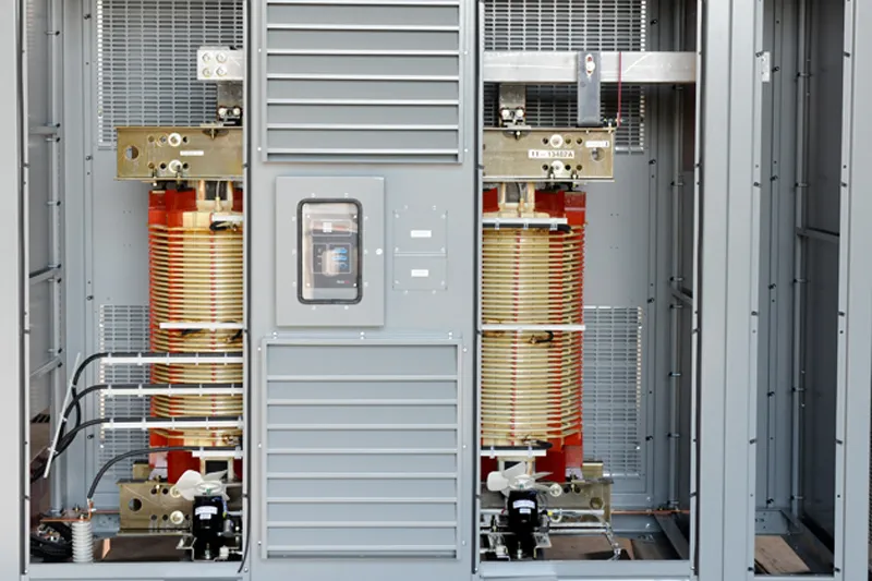 Interior view of industrial electrical transformer with dual copper coils, control panel, and safety switches