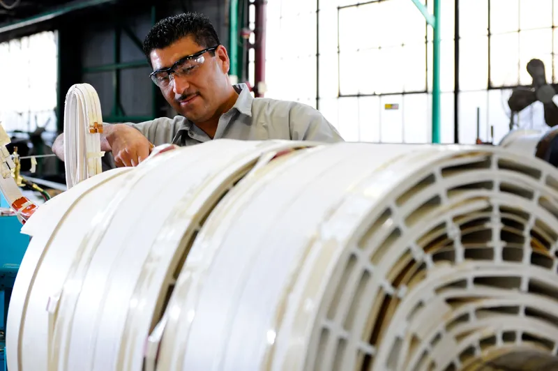 Technician inspecting white electrical transformer coils in manufacturing facility