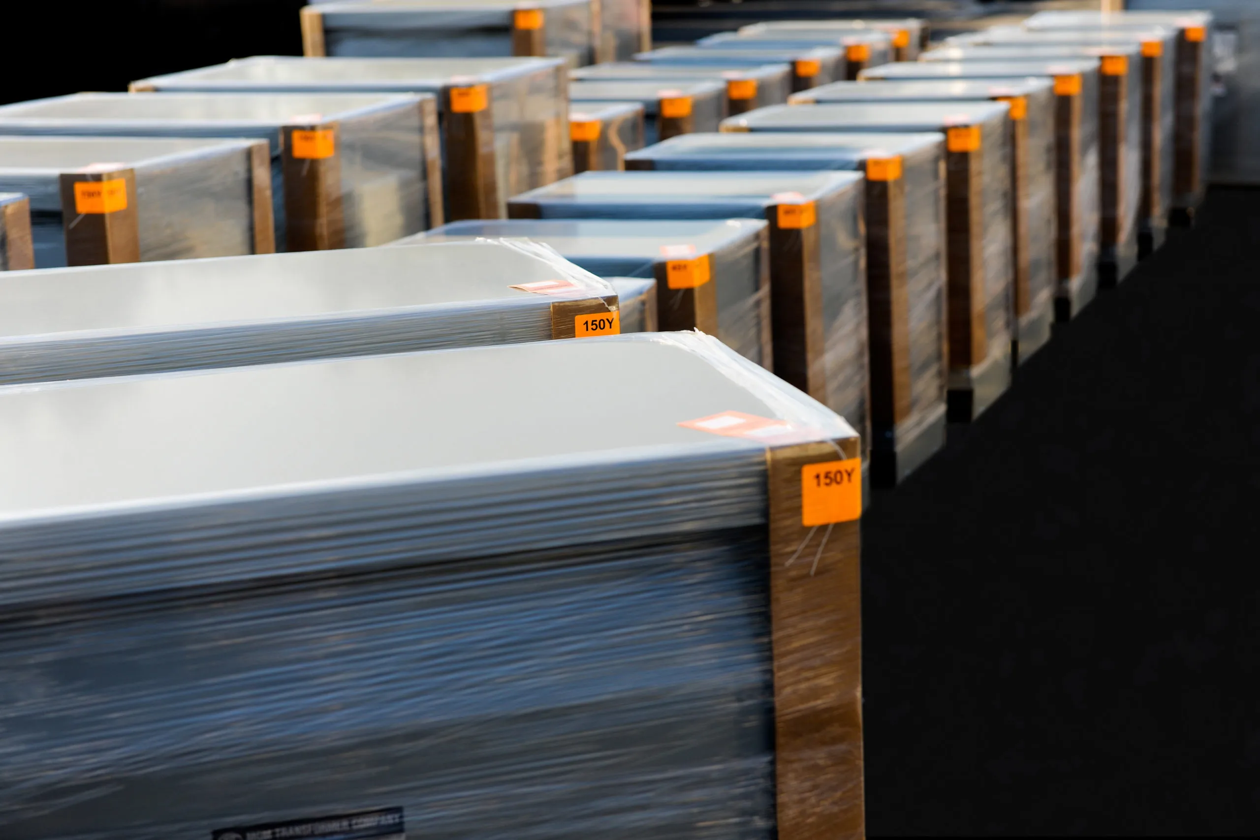 Rows of wrapped aluminum sheets marked with orange 150Y labels in industrial warehouse storage