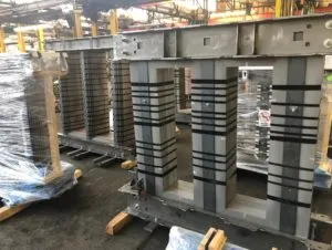 Stacked electrical steel transformer cores with gray and black layered construction in industrial warehouse