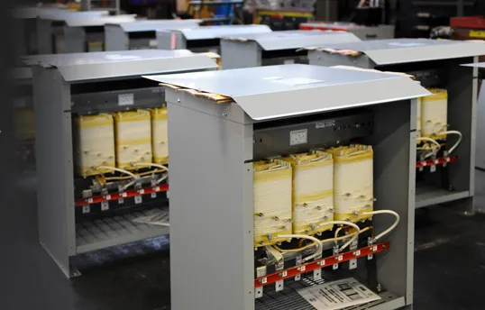 MGM Transformers industrial transformer units with yellow capacitors and red components in manufacturing facility