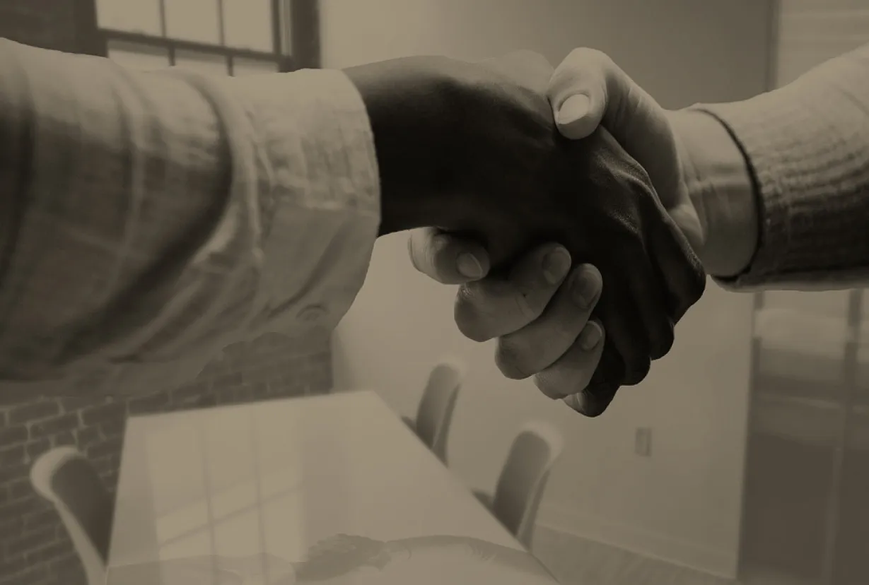 Two professionals shaking hands in business meeting, symbolizing partnership and welcoming new team members