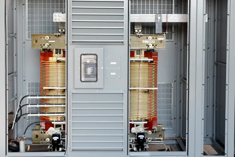 Interior view of industrial transformer with coiled copper windings, control panel, and ventilation system
