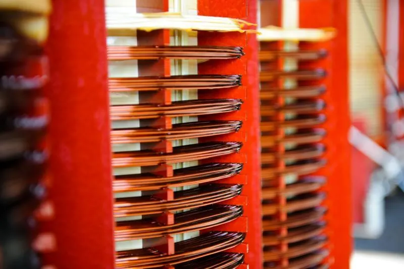 Stacked red transformer coils with copper windings and metal connectors in product photo gallery