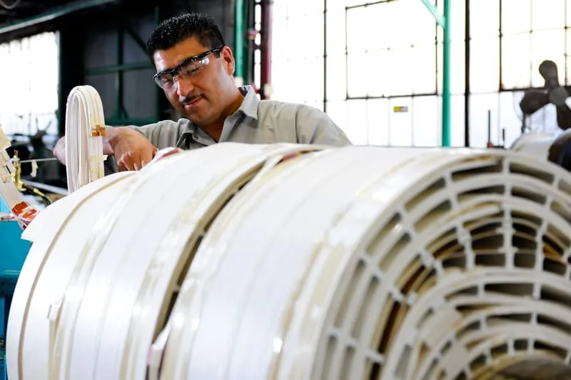 Technician inspecting white transformer coils in manufacturing facility workshop