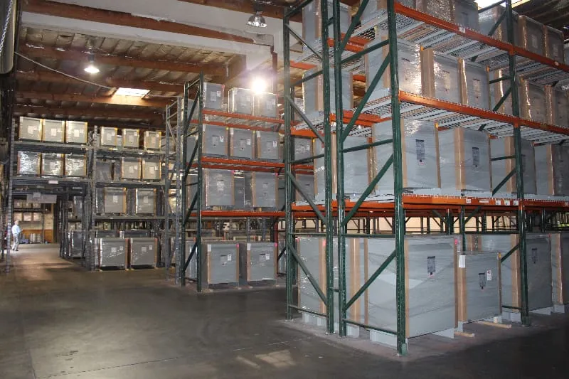 Industrial warehouse interior with green and orange pallet racking systems storing electrical transformers and equipment