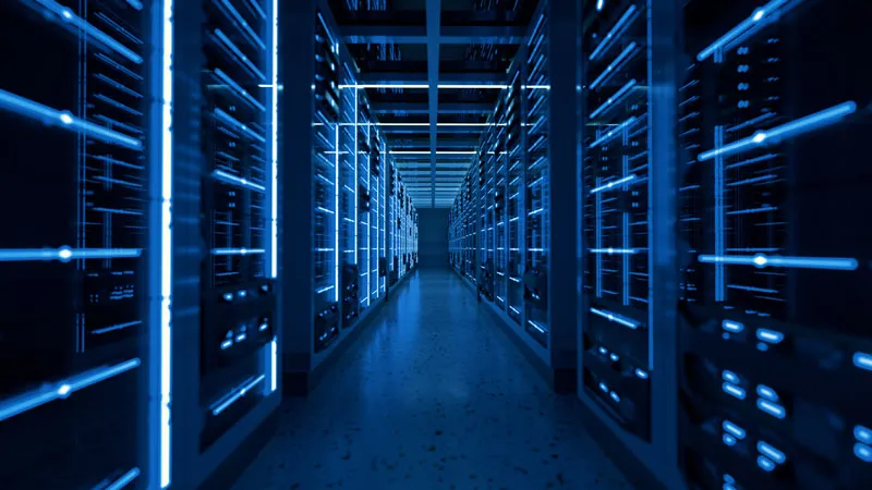 Data center server room with illuminated blue server racks lining both sides of a corridor
