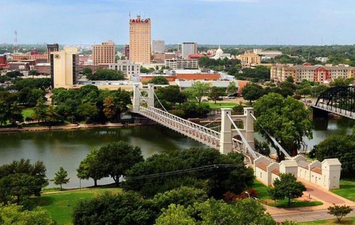 Waco, Texas skyline with suspension bridge spanning river, green parks, and downtown buildings