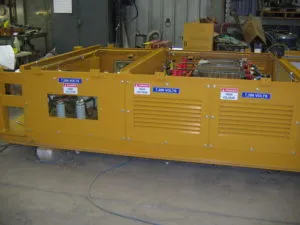 Low-profile transformer unit painted bright yellow with multiple electrical components and ventilation panels for