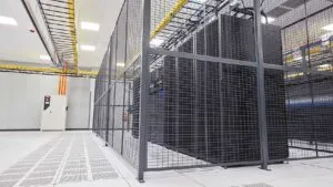   Industrial transformer facility with secured mesh enclosure, yellow overhead crane systems, and safety equipment in